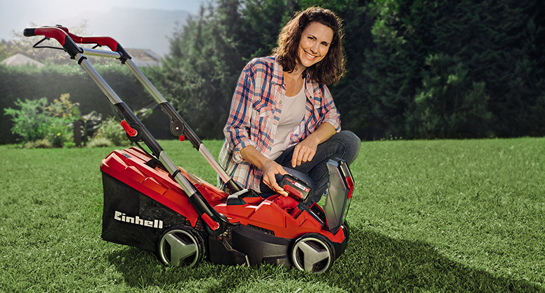 a woman puts a battery in the lawn mower