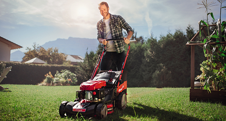 a man pushes the lawn mower as he cuts the grass